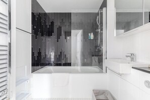 Ein modernes Badezimmer mit Duschkabine aus Glas, einer Badewanne und einem weißen Waschbecken.