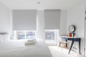 Ein modernes Hotelzimmer mit einem großen Bett, einem Schreibtisch und Blick auf die Stadt.