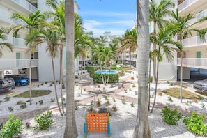 Une cour d’hôtel agrémentée de palmiers, d’une piscine et d’un chemin en briques.