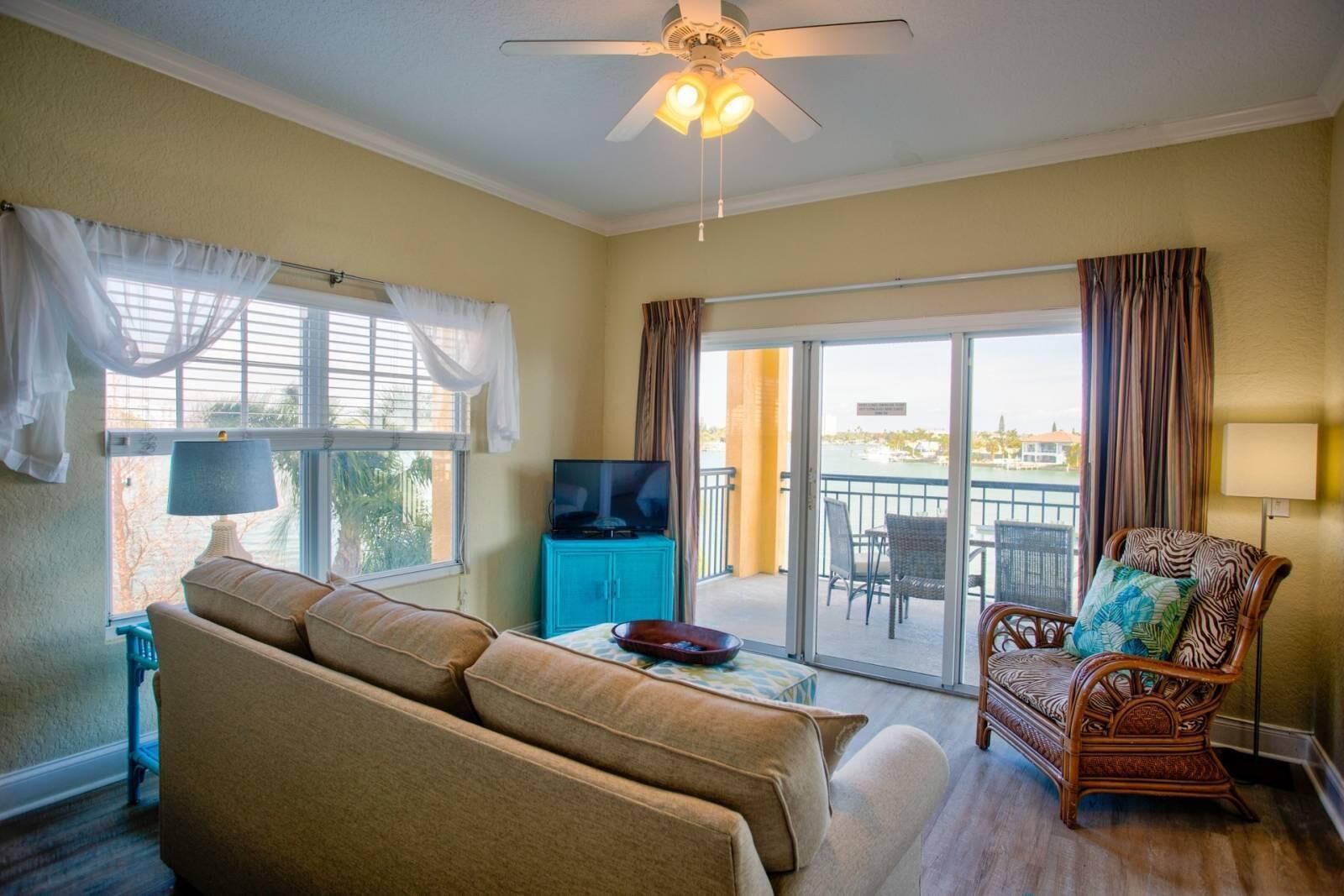 Un salon comprenant un canapé, un téléviseur, une table à manger et une chaise. Il y a un balcon avec vue sur l’eau.
