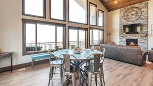 A spacious living area with a large round table and chairs, a built-in fireplace, and a stone accent wall.