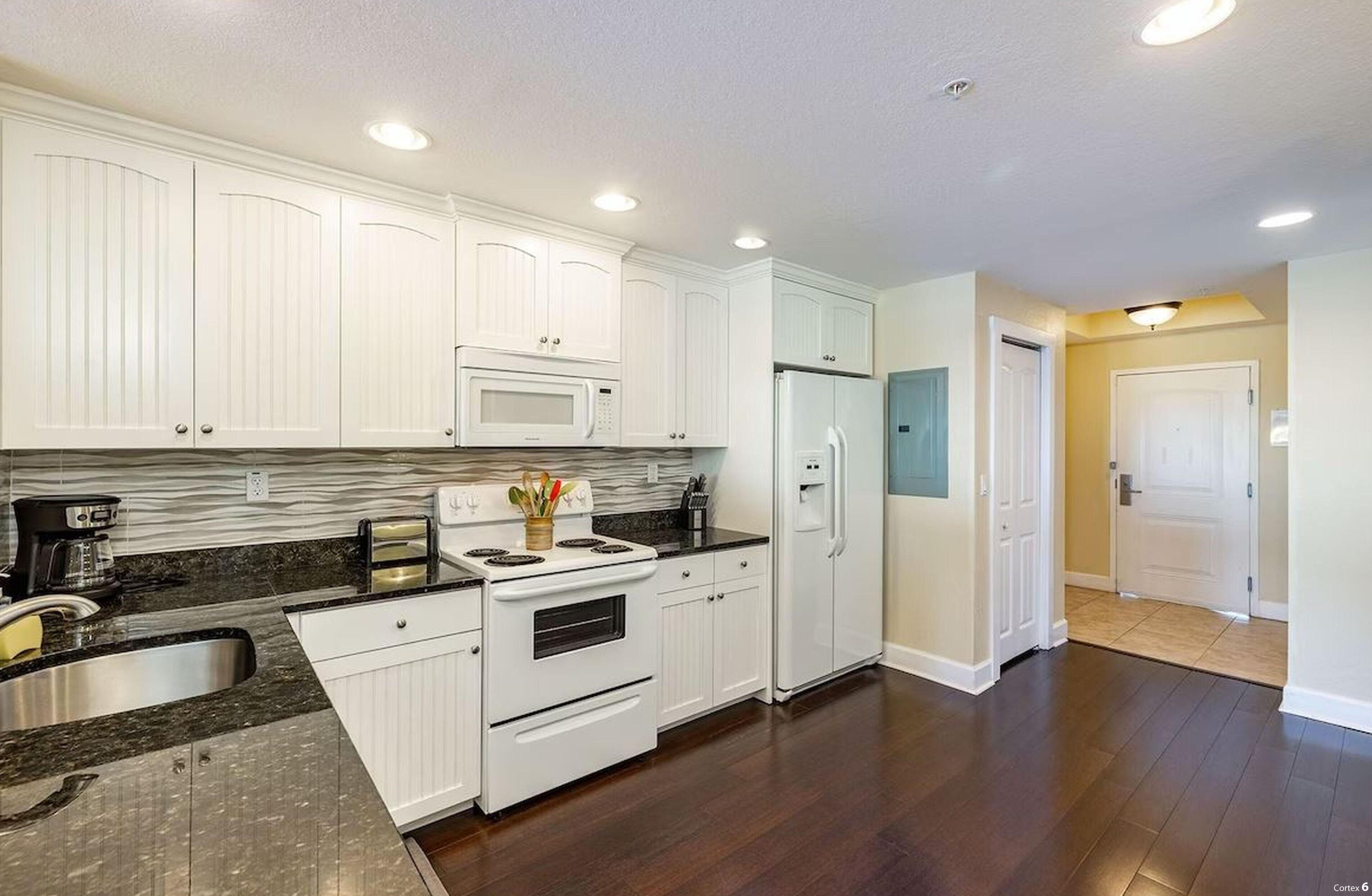 A kitchen with white cabinets, a microwave, a refrigerator, and a stove.