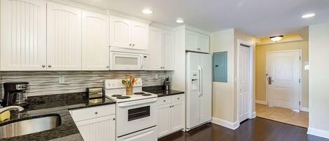 A kitchen with white cabinets, a microwave, a refrigerator, and a stove.