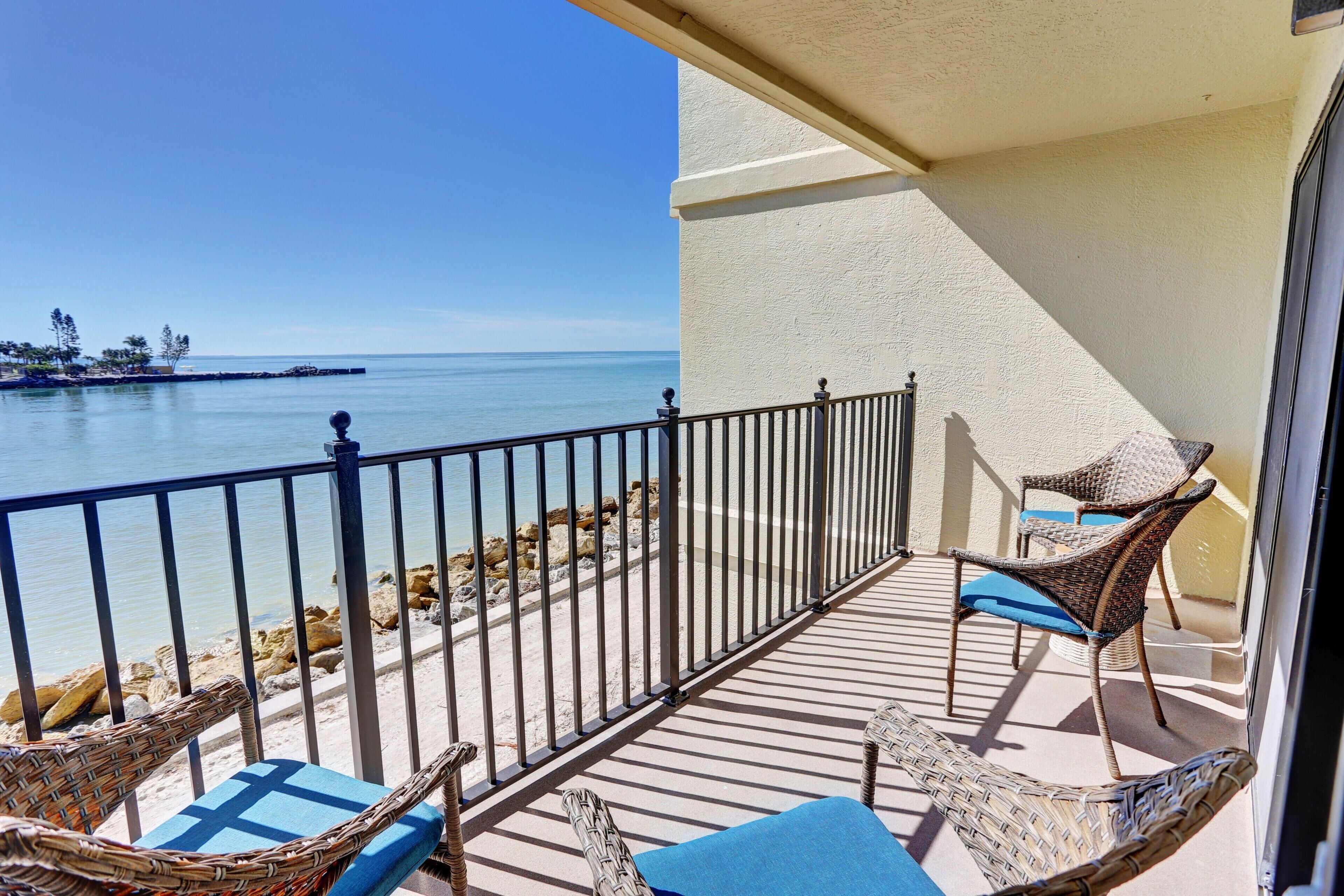 A balcony with wicker chairs and a view of the beach.