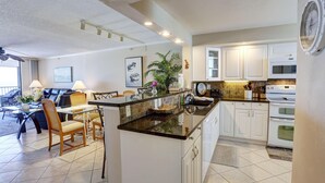A modern kitchen with white cabinets, a black countertop, and a dining area with a table and chairs.