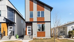 Un immeuble résidentiel moderne à deux étages, doté d’une façade grise, d’éléments décoratifs en bois et de grandes fenêtres.