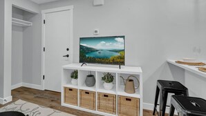 Un salon moderne avec un meuble TV blanc, des paniers en osier et une porte.