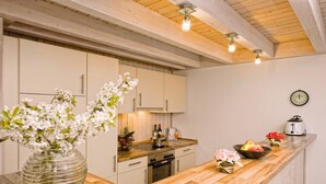 A modern kitchen with wooden cabinets, a wooden countertop, and a clock on the wall.