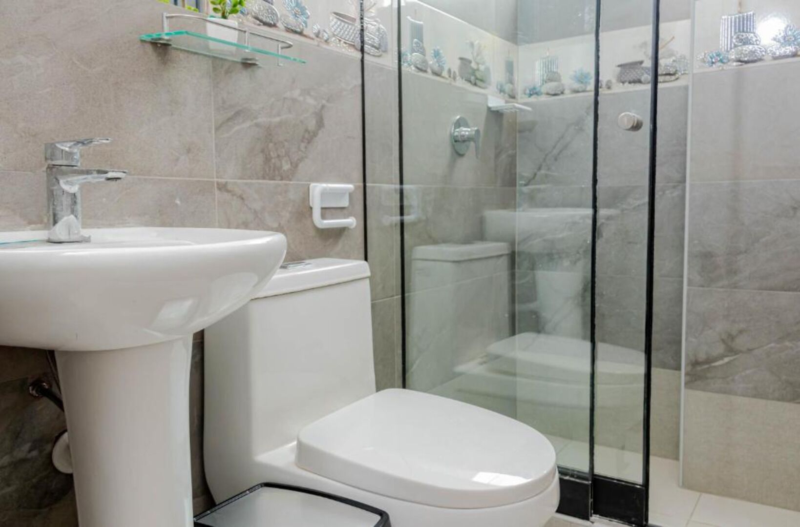 A modern bathroom with a glass-enclosed shower, a white sink, and a toilet.