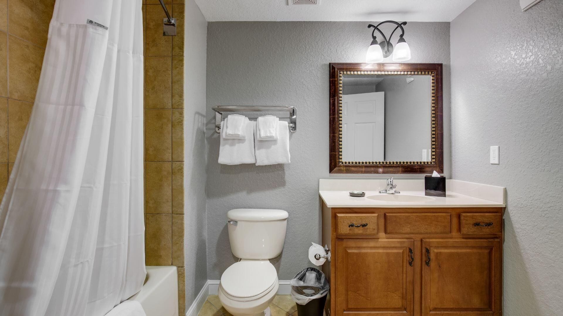 Une salle de bain équipée d’une douche, de toilettes, d’un lavabo et de meubles en bois.