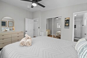 Relax in a spacious bedroom with a large bed, dresser, and mirror, plus a convenient bathroom with a glass shower enclosure.