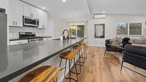 Une cuisine moderne avec des meubles blancs, une cuisinière en acier inoxydable et un grand îlot central doté de tabourets de bar.