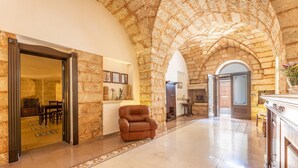 A spacious lobby with a stone archway, a leather armchair, and a dining area visible through an open doorway. - Palazzo Lily - Racale (Racale)