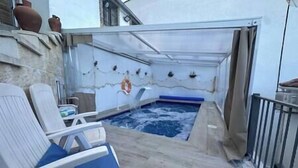 A pool area with a hot tub, lounge chairs, and a lifebuoy on the wall.