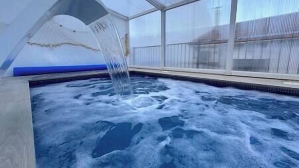 An indoor swimming pool with a waterfall feature.