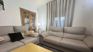 A living room with a beige sofa, a yellow coffee table, and a cabinet with glass doors.