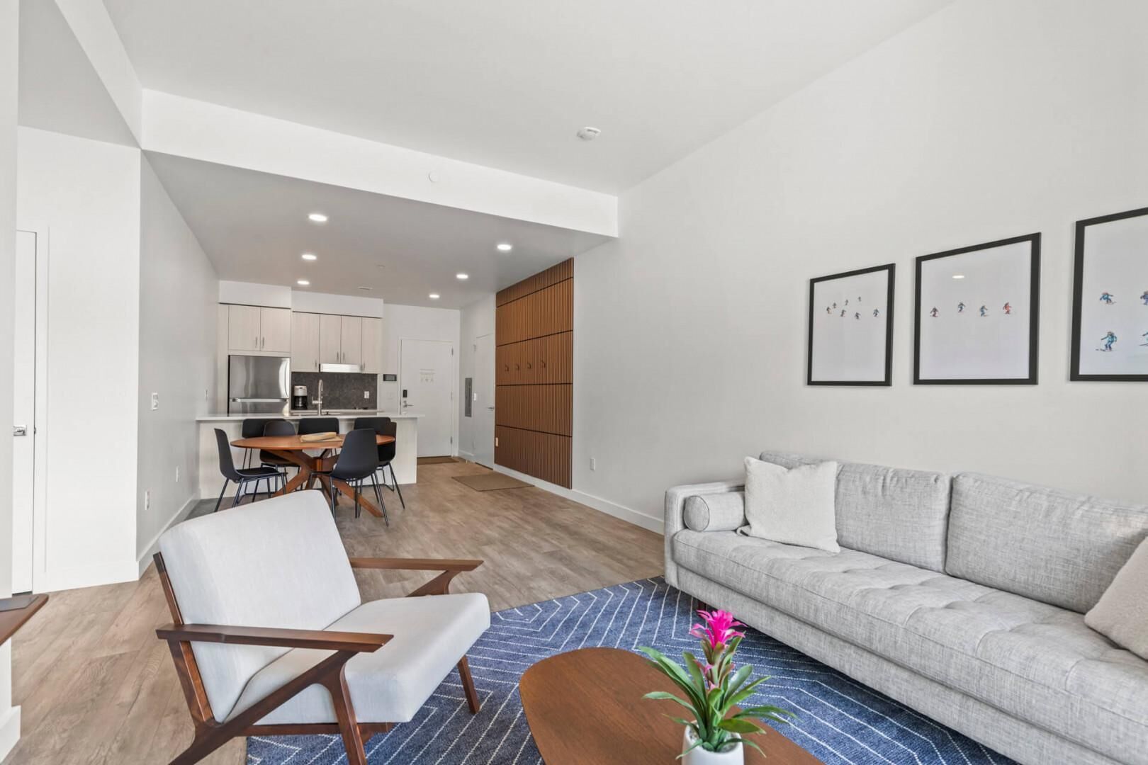 Uma sala de estar moderna com sofá, poltronas, mesa de centro e um espaço de jantar com mesa e cadeiras.