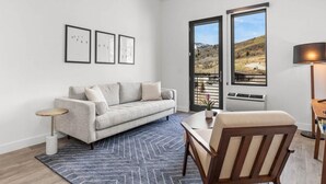 A living room with a sofa, a coffee table, a chair, a rug, and framed pictures on the wall. - Pioche Village by Park City Vacations (Park City)