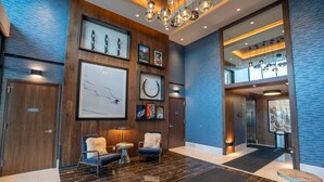 A modern lobby with a wooden reception desk, framed artwork, seating area with chairs, and a marble floor. - Pioche Village by Park City Vacations (Park City)