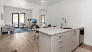 A modern kitchen with a large island, a dining area with a sofa and chairs, and a living room with a TV and seating. - Pioche Village by Park City Vacations (Park City)