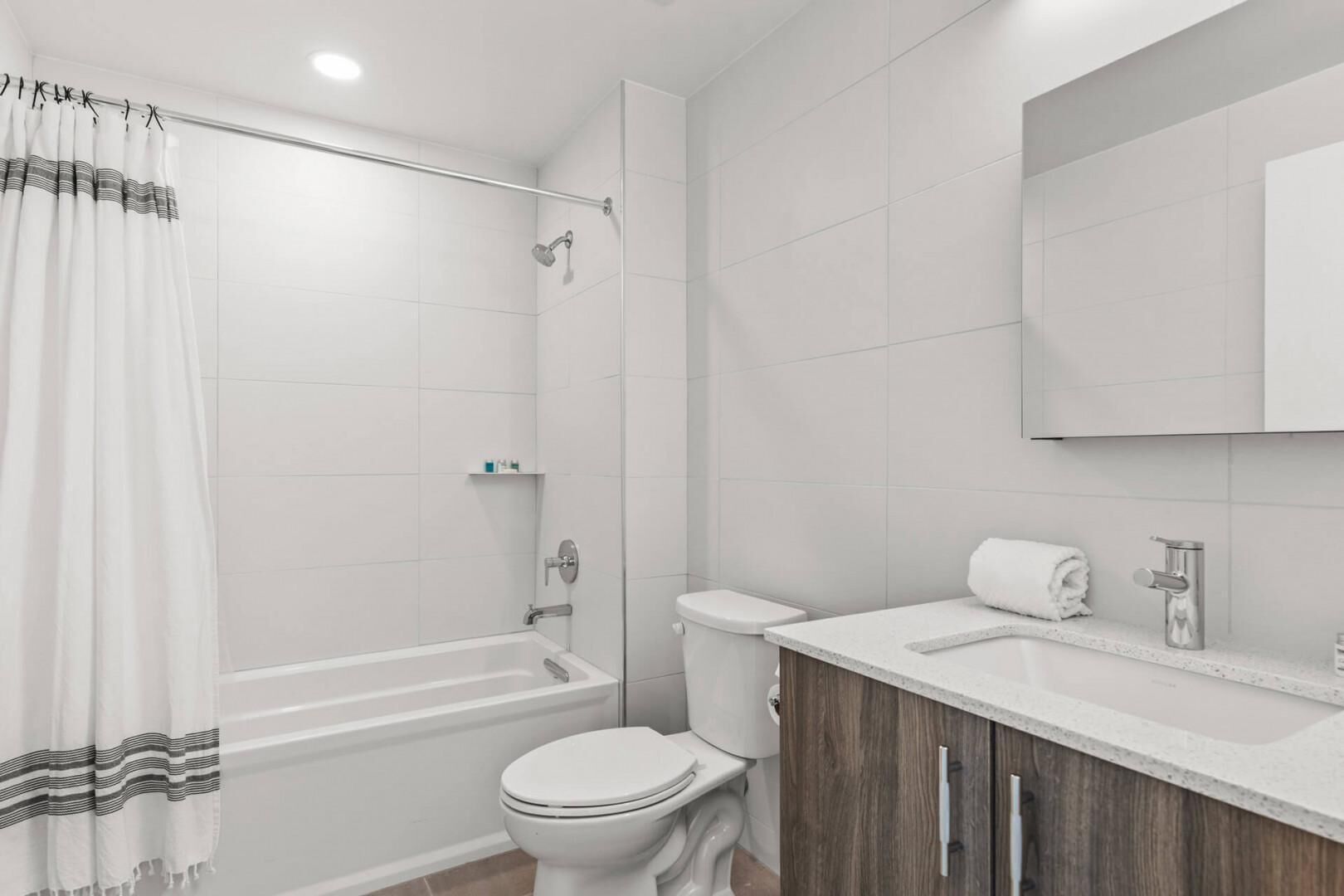 A modern bathroom with a bathtub, toilet, and vanity.