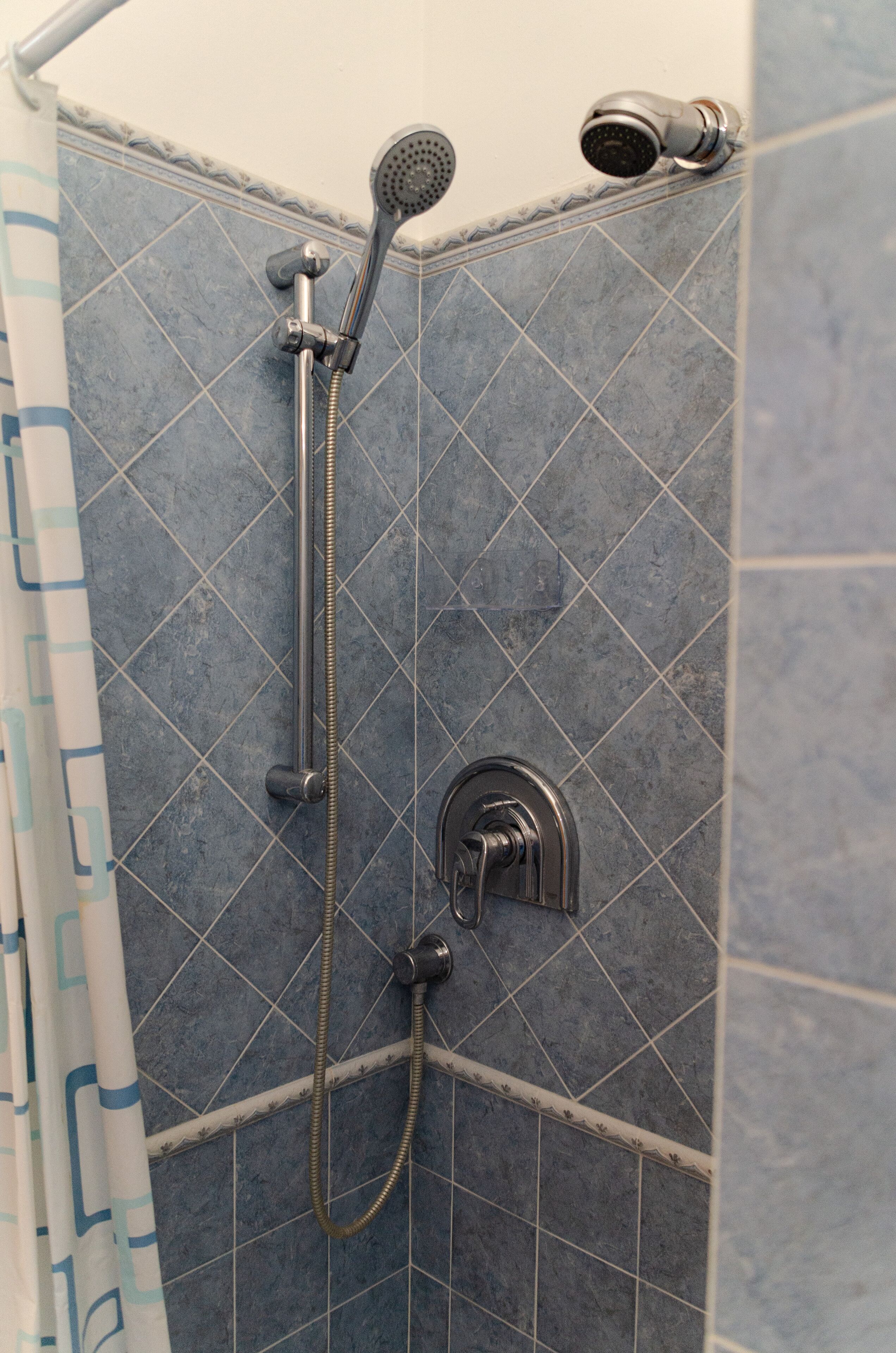 Un espace douche équipé d’un pommeau de douche à main et d’un robinet mural.