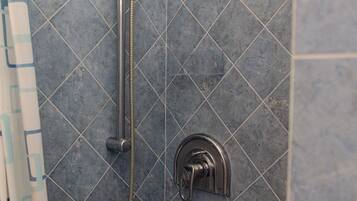 Un espace douche équipé d’un pommeau de douche à main et d’un robinet mural.