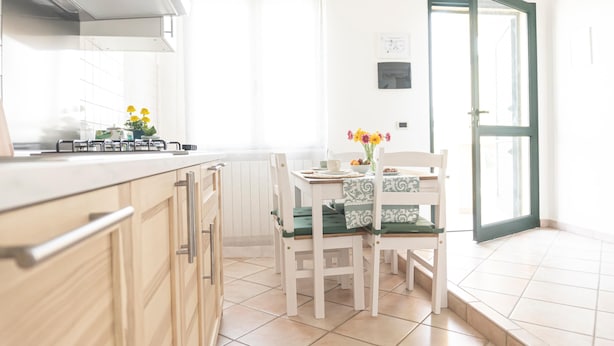 Una cocina con mesa, sillas y ventana con cortinas.