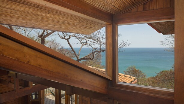 Un intérieur en bois avec une grande fenêtre donnant sur une vue panoramique de la côte.
