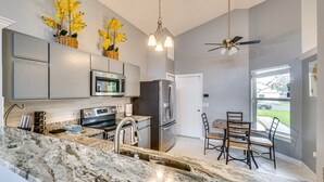 Una cocina moderna con encimeras de granito, electrodomésticos de acero inoxidable y un comedor con mesa y sillas.