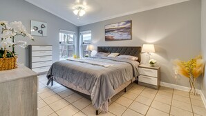 Un dormitorio con cama, mesitas de noche, cómoda y ventilador de techo.