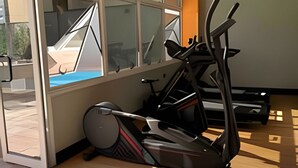 Une salle de sport équipée de matériel d’exercice, dotée de grandes fenêtres et d’un ventilateur de plafond.