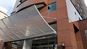 Un bâtiment moderne doté d’une façade incurvée, de nombreux balcons et d’un espace d’entrée abrité.
