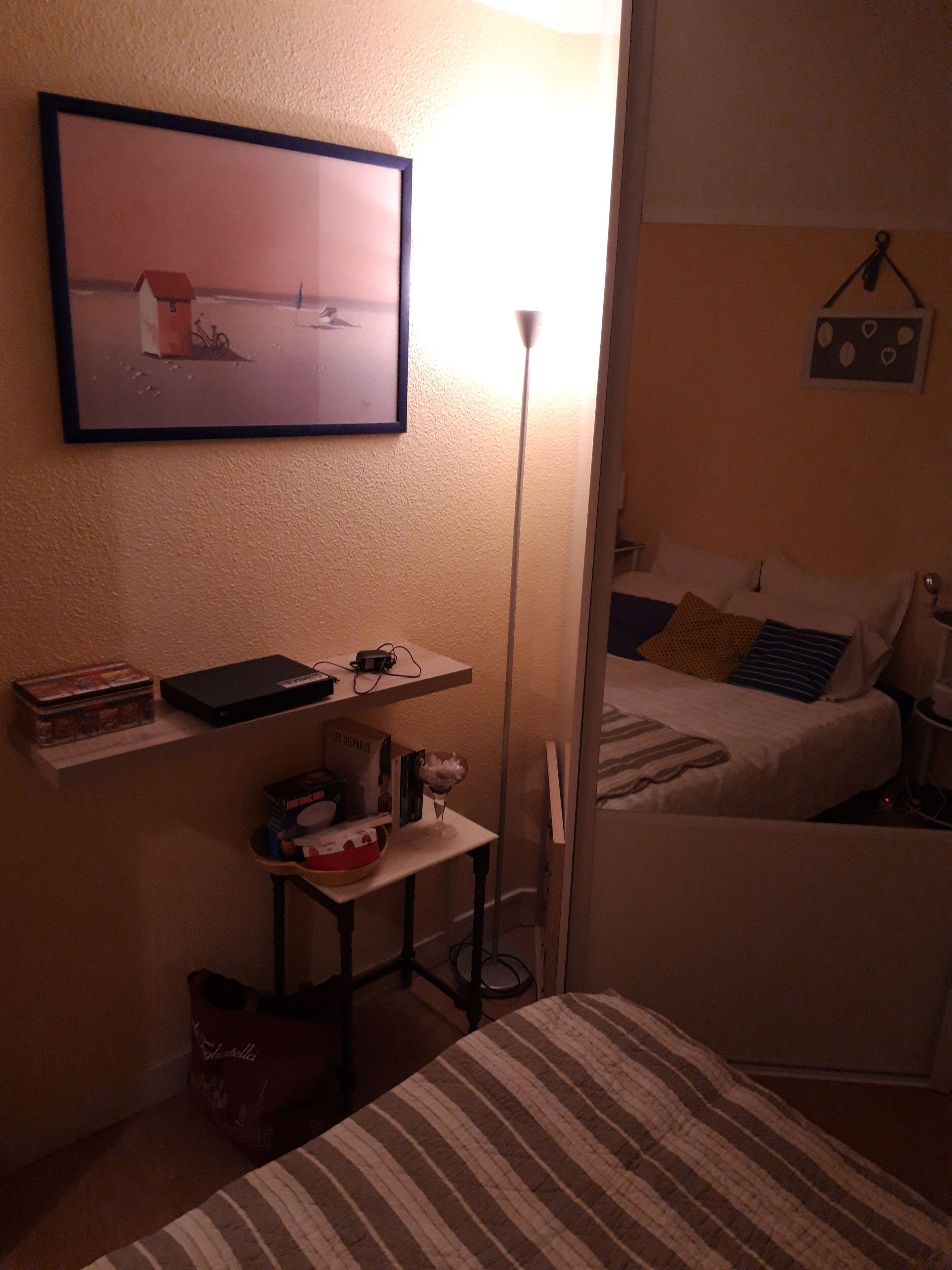 Een knus slaapkamer met een bed, nachtkastje en een ingelijste foto aan de muur.
