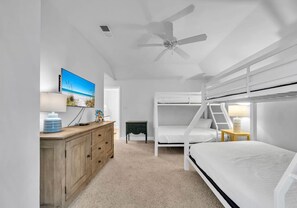 Une chambre avec des lits superposés, un ventilateur de plafond, une télévision et une commode.