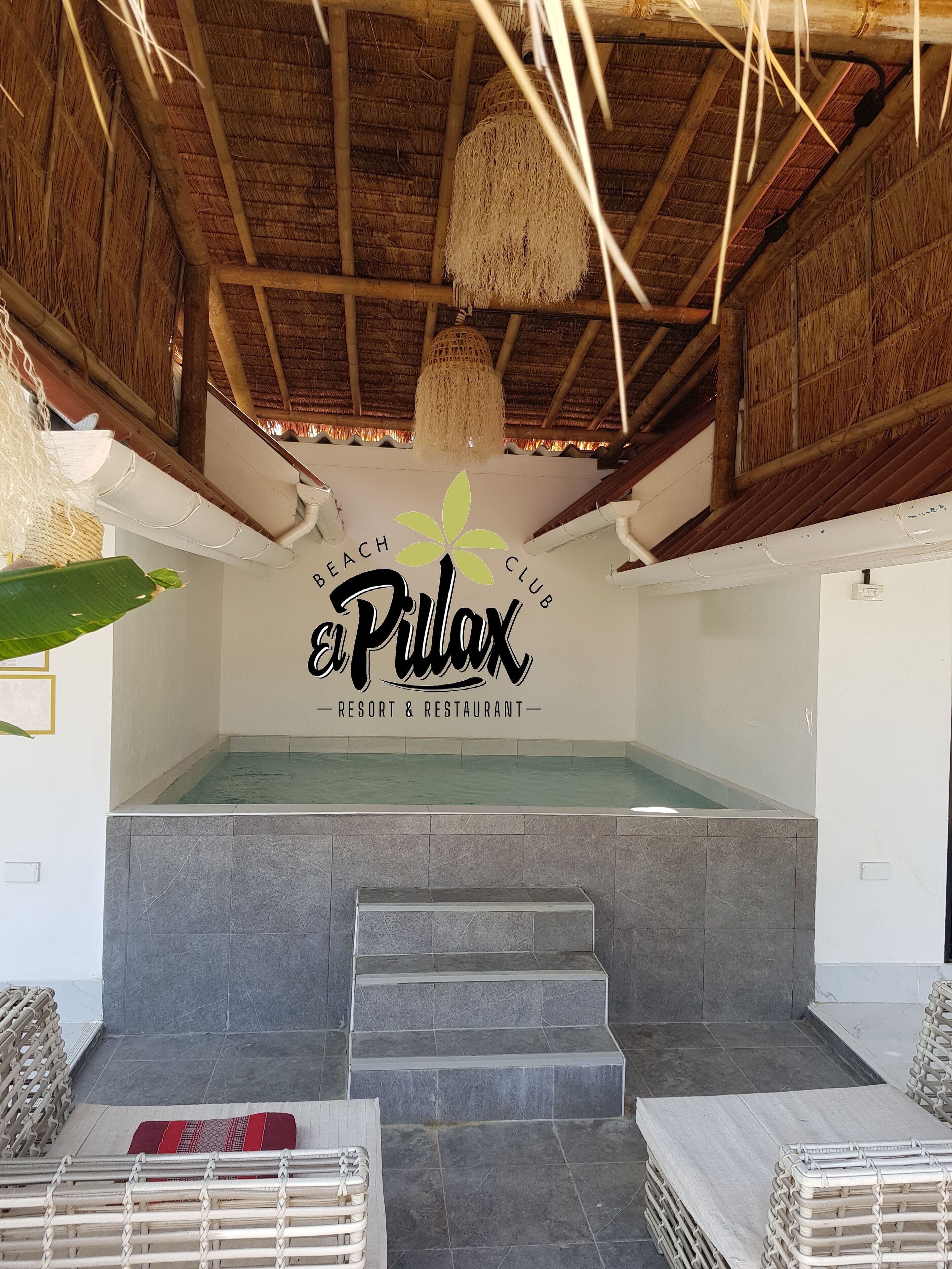 A pool area with a sign reading 'El Pilón Resort & Restaurant' and a staircase leading to the pool.