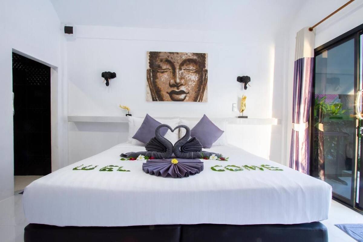 Habitación de hotel con una cama decorada con un arreglo de almohadas con forma de cisne y un cartel que dice 'BIENVENUE'.