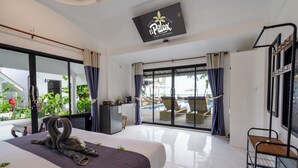 Quarto de hotel moderno com cama, escrivaninha e vista para uma piscina e área externa com assentos.