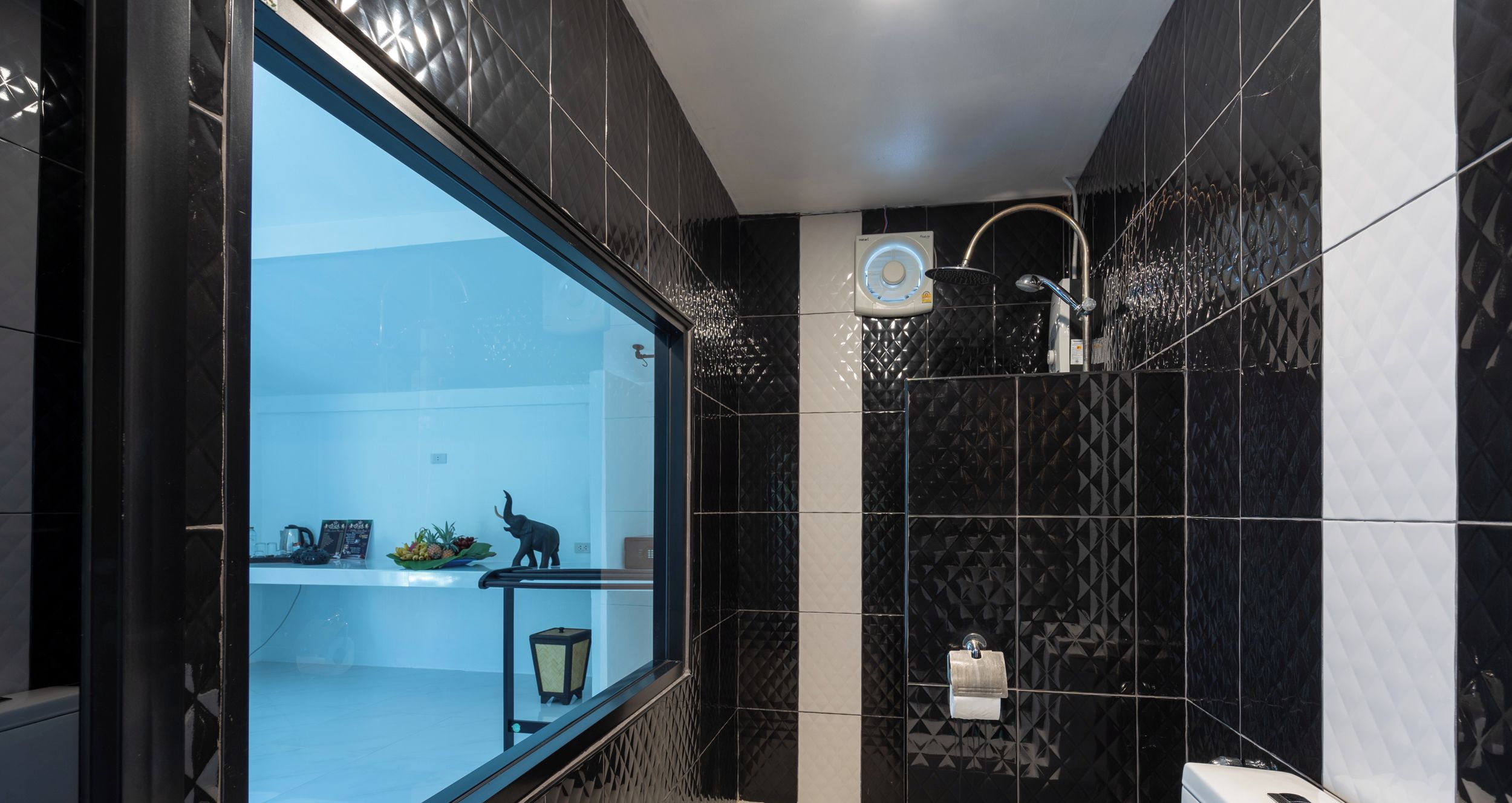 Une salle de bain moderne avec une paroi en verre, un espace douche et un porte-rouleau de papier toilette apparent.