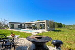Ein modernes Haus mit Pool, Sitzgelegenheiten im Freien und Grillplatz.