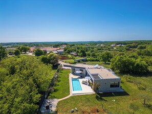 Ein modernes Haus mit Swimmingpool, umgeben von üppiger Vegetation und blauem Himmel.