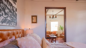 Een slaapkamer met een groot bed, een nachtkastje, een lamp en een lijst met een afbeelding aan de muur.