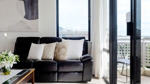 Relax in this stylish living room with a sofa, table, and balcony view.