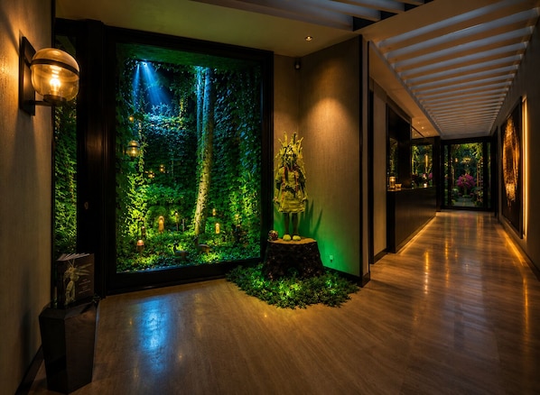 Un couloir avec un grand aquarium, une statue et un plancher en bois.