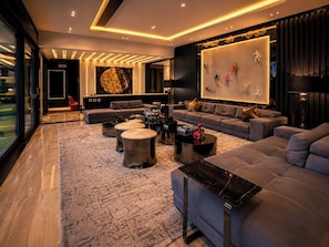 Un salon moderne avec un grand canapé, une table basse et un téléviseur fixé au mur.