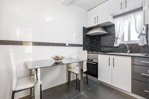 Enjoy cooking in this kitchen with sleek cabinetry, a glass-top dining table, and oven.