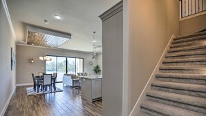 Une cuisine moderne dotée d’un îlot central, d’un coin repas avec une table et des chaises, et d’un escalier menant à l’étage supérieur.