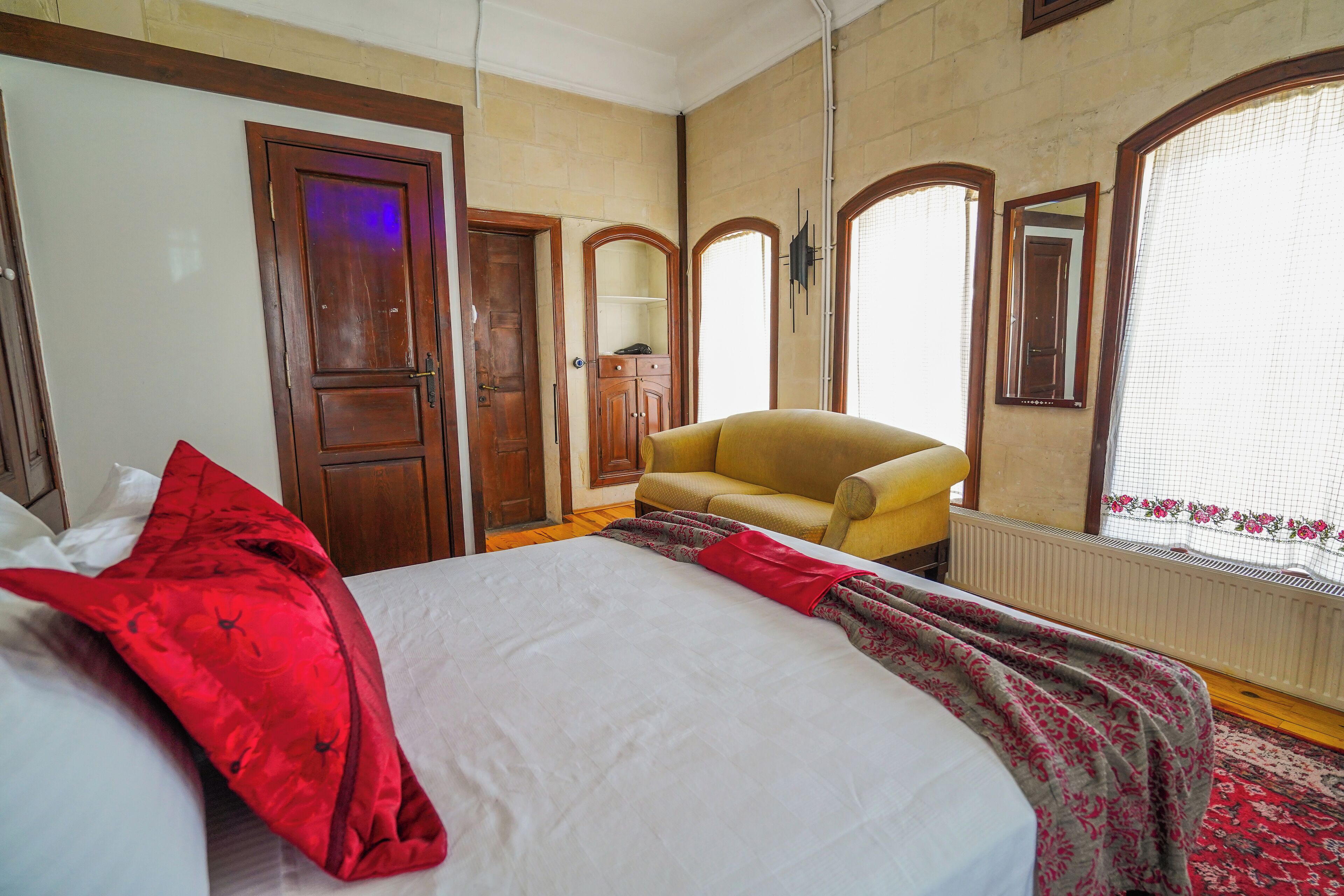 Un dormitorio con una cama, un sillón amarillo, un armario de madera y un espejo.
