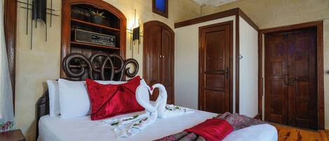 A hotel room with a bed, a wooden headboard, a wall-mounted radio, and two wooden doors.