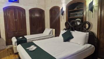 A room with two beds, wooden wardrobes, a radio, and a small blue-lit window.